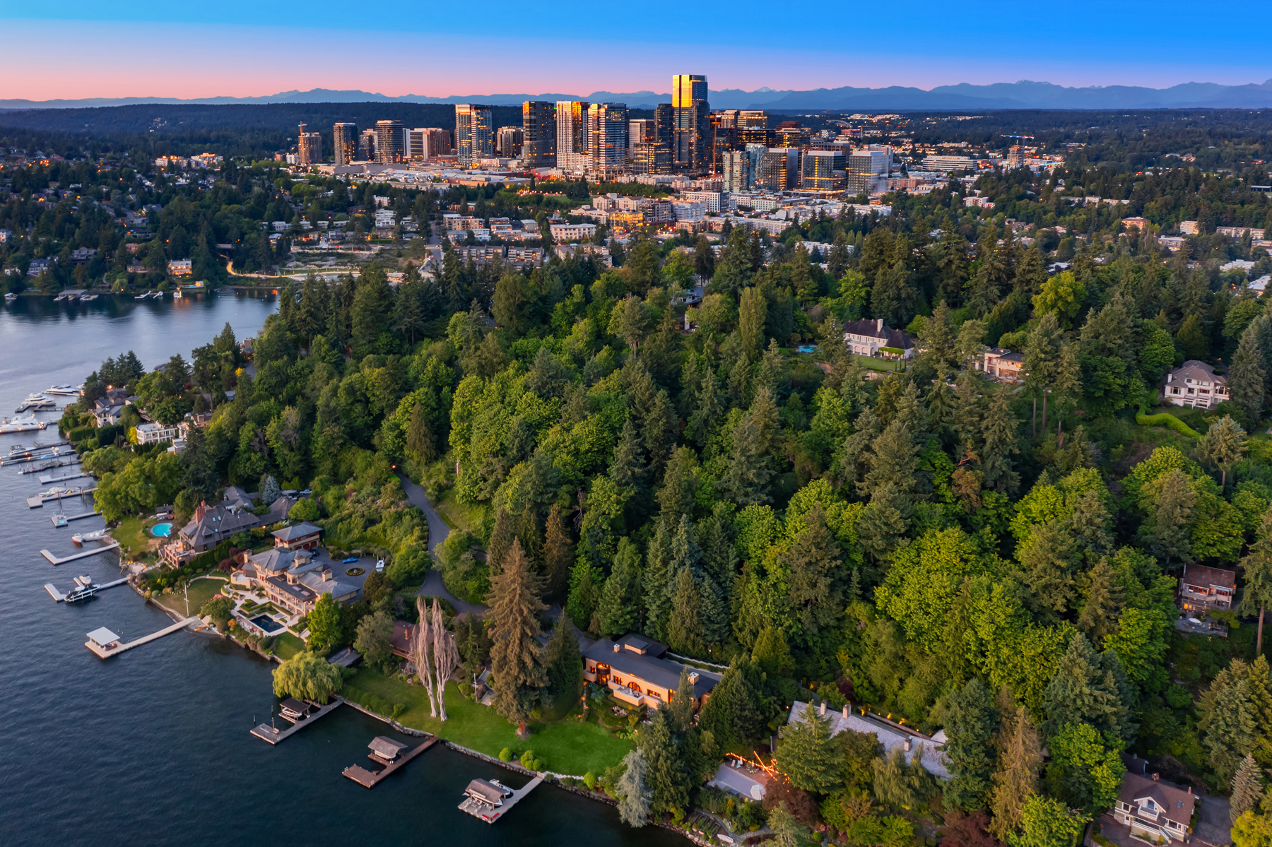 Aerial of the home on the western shore of Lake Washington with downtown Bellevue and the Cascades in the distance